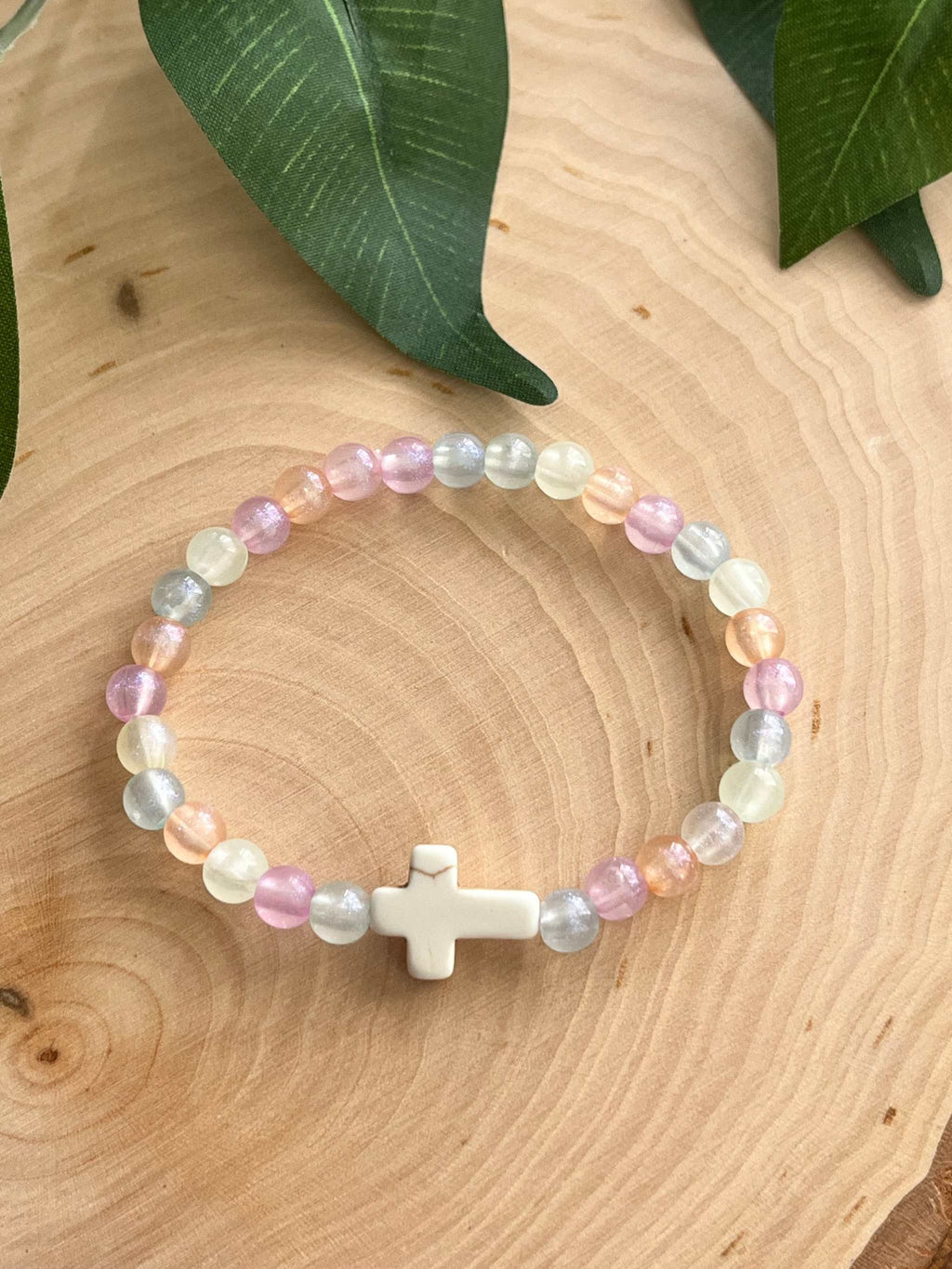 Colorful pastel bead bracelet with a white cross charm centered on the band.