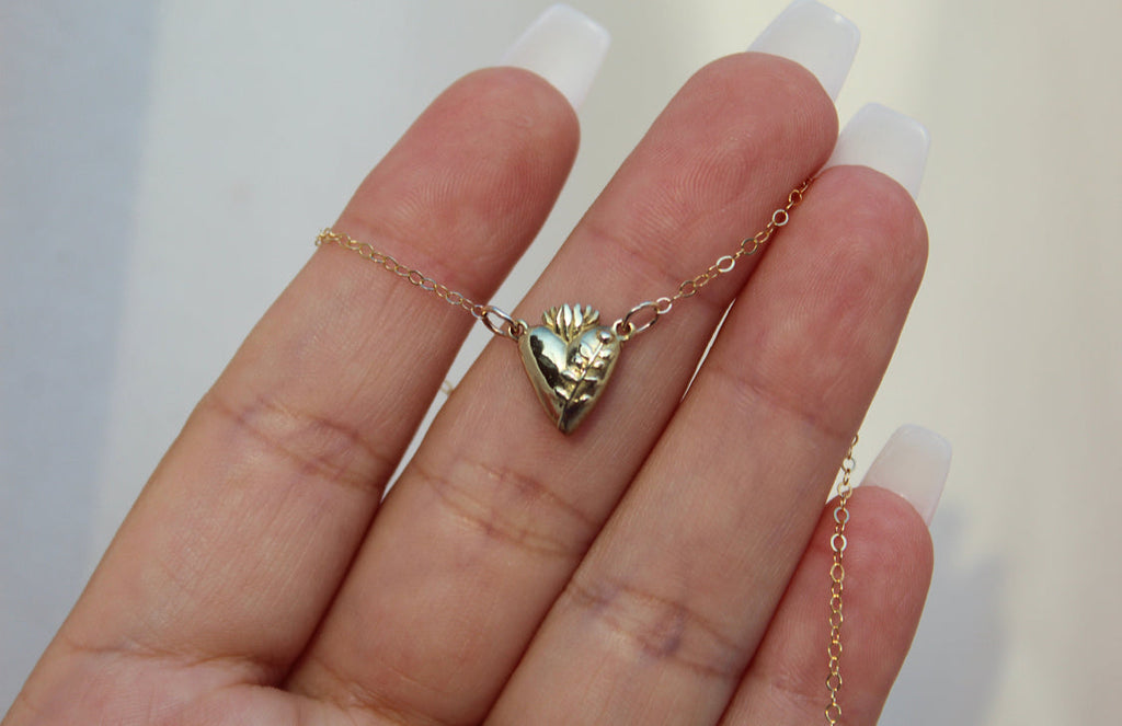 Gold-tone heart pendant necklace close-up on hand with chain
