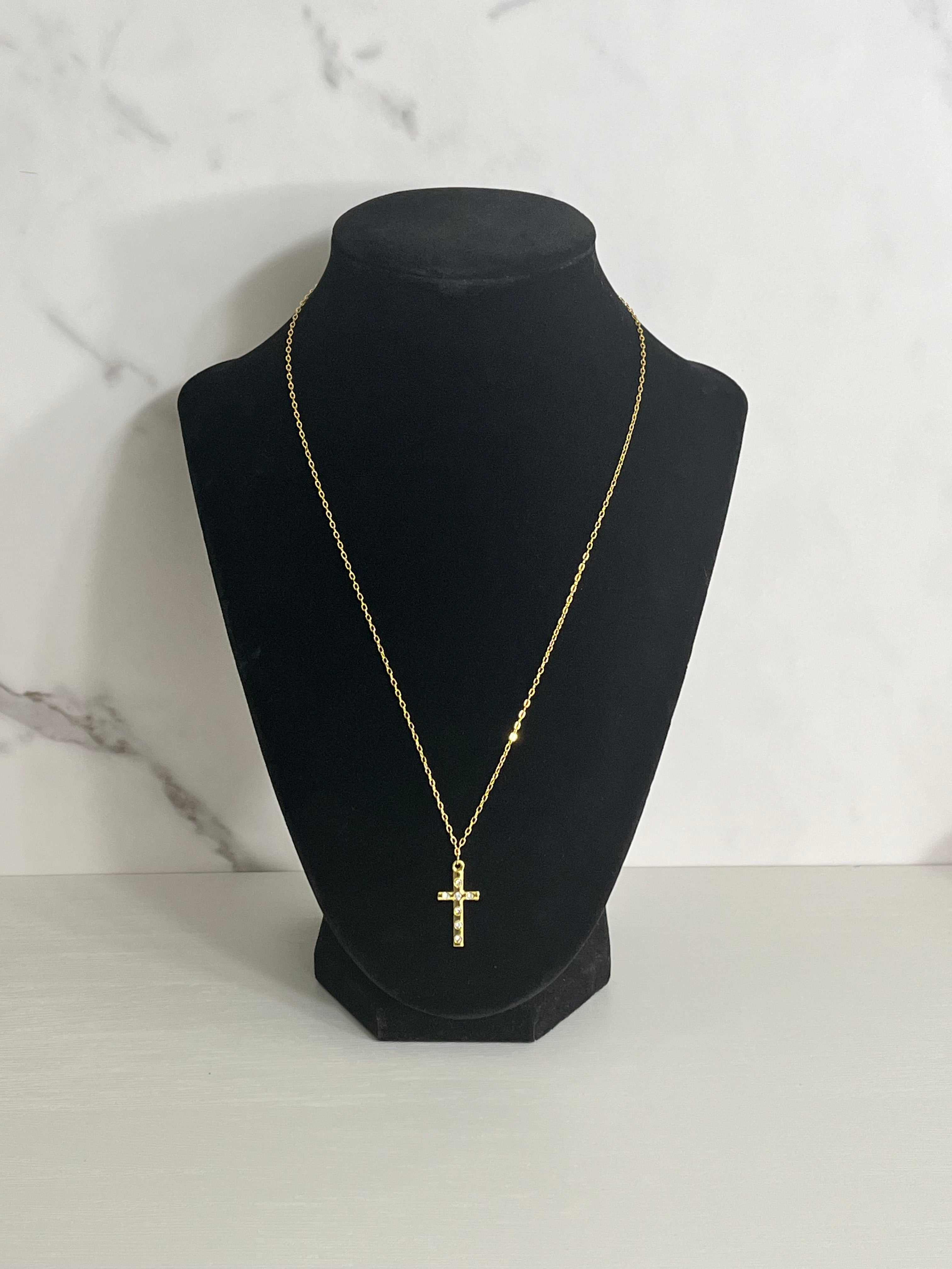 Gold cross pendant necklace on black bust, cross charm on thin chain