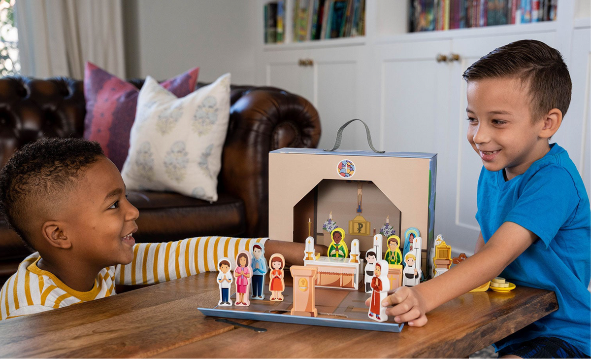 Two children smiling with church playset on table featuring standing character figures
