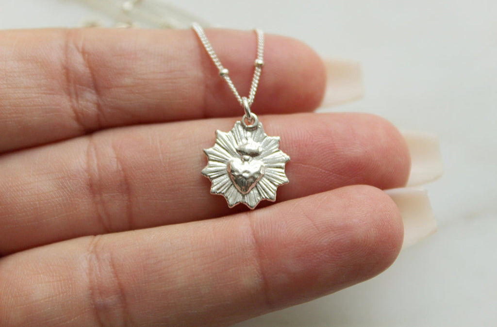 Sterling silver scalloped heart pendant necklace shown on a hand