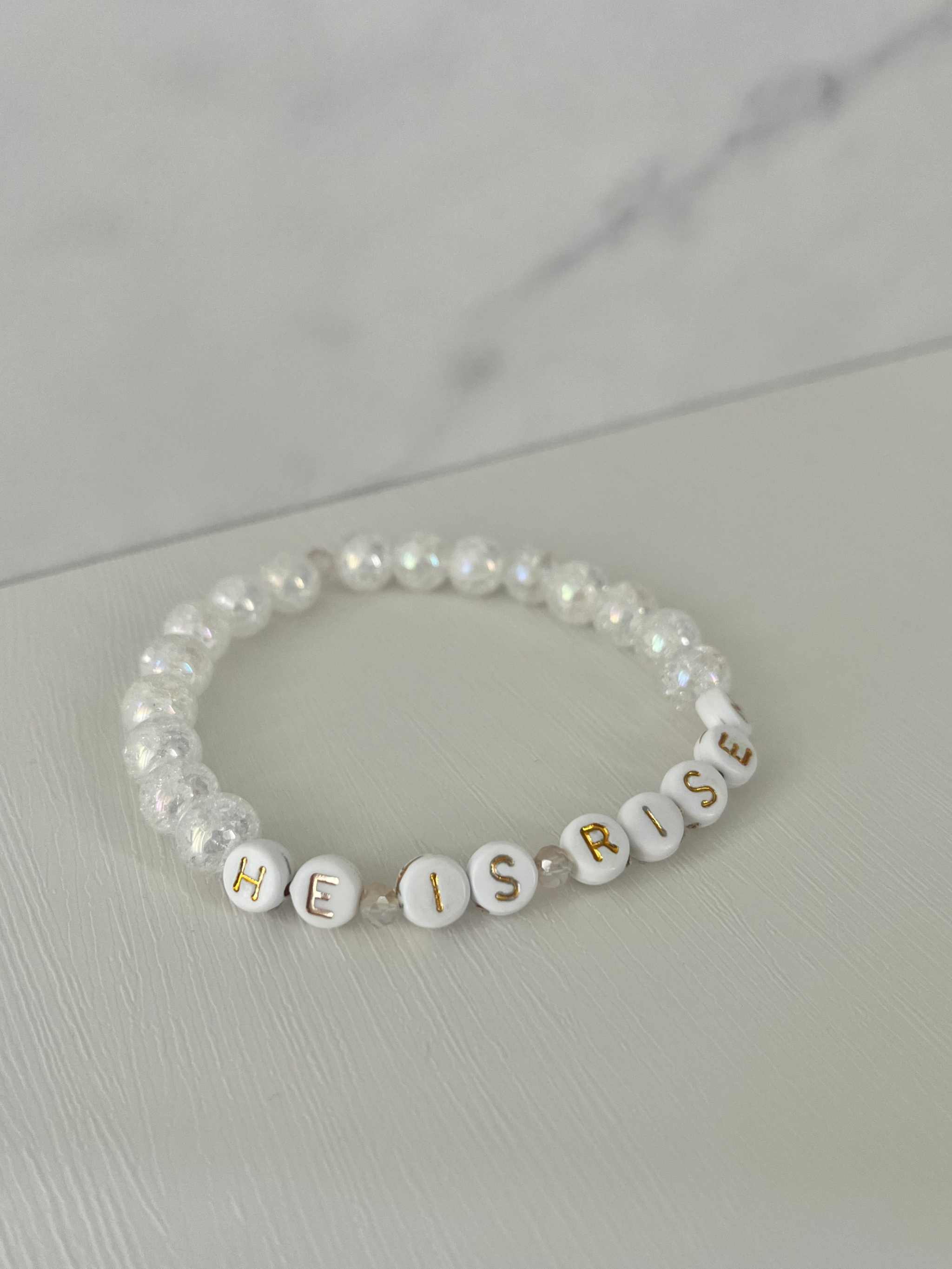 White bead bracelet with 'HE IS RISEN' letter beads and small cross charm