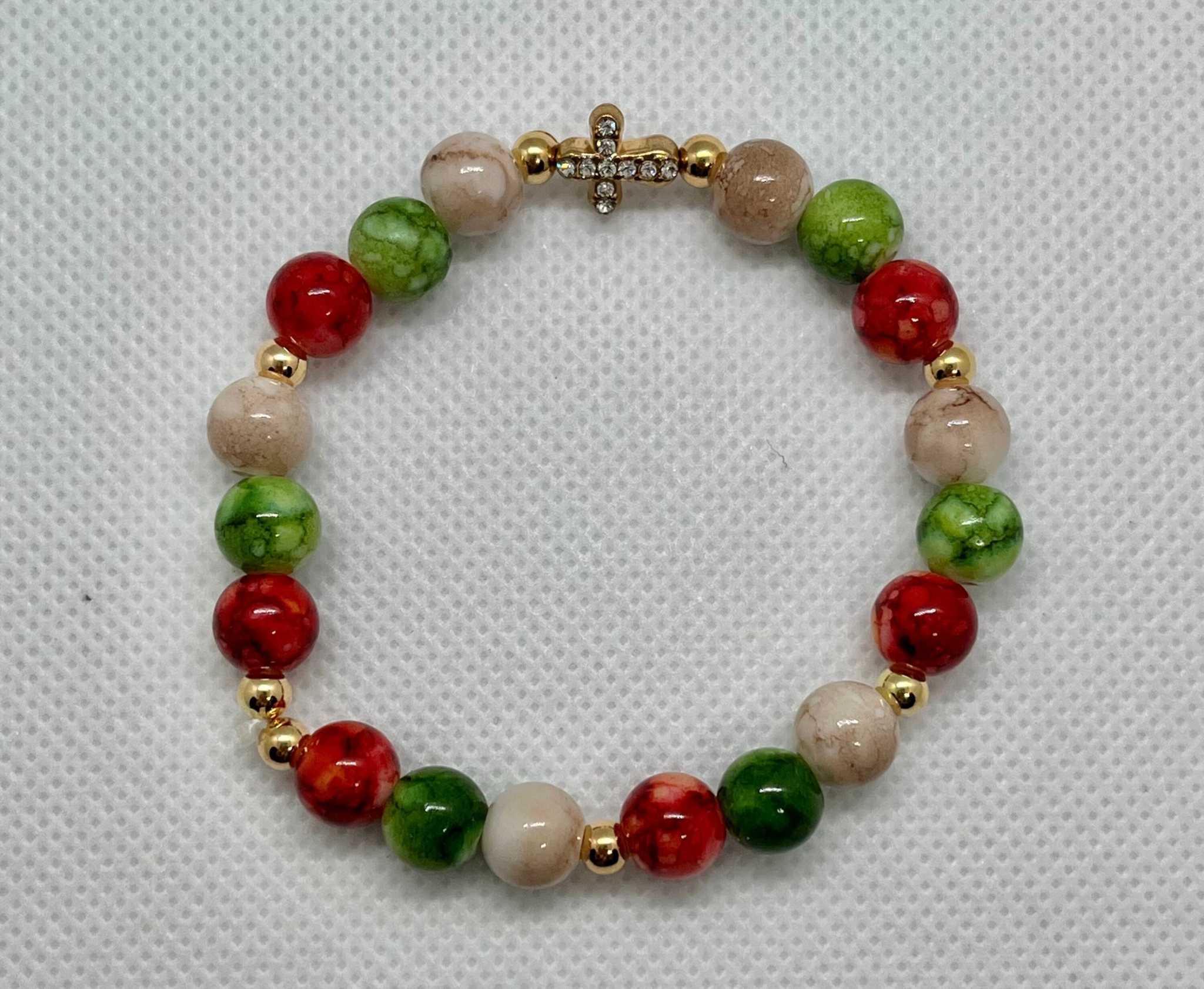 Bead bracelet with marbled beige, green, and red beads and a gold jeweled cross charm