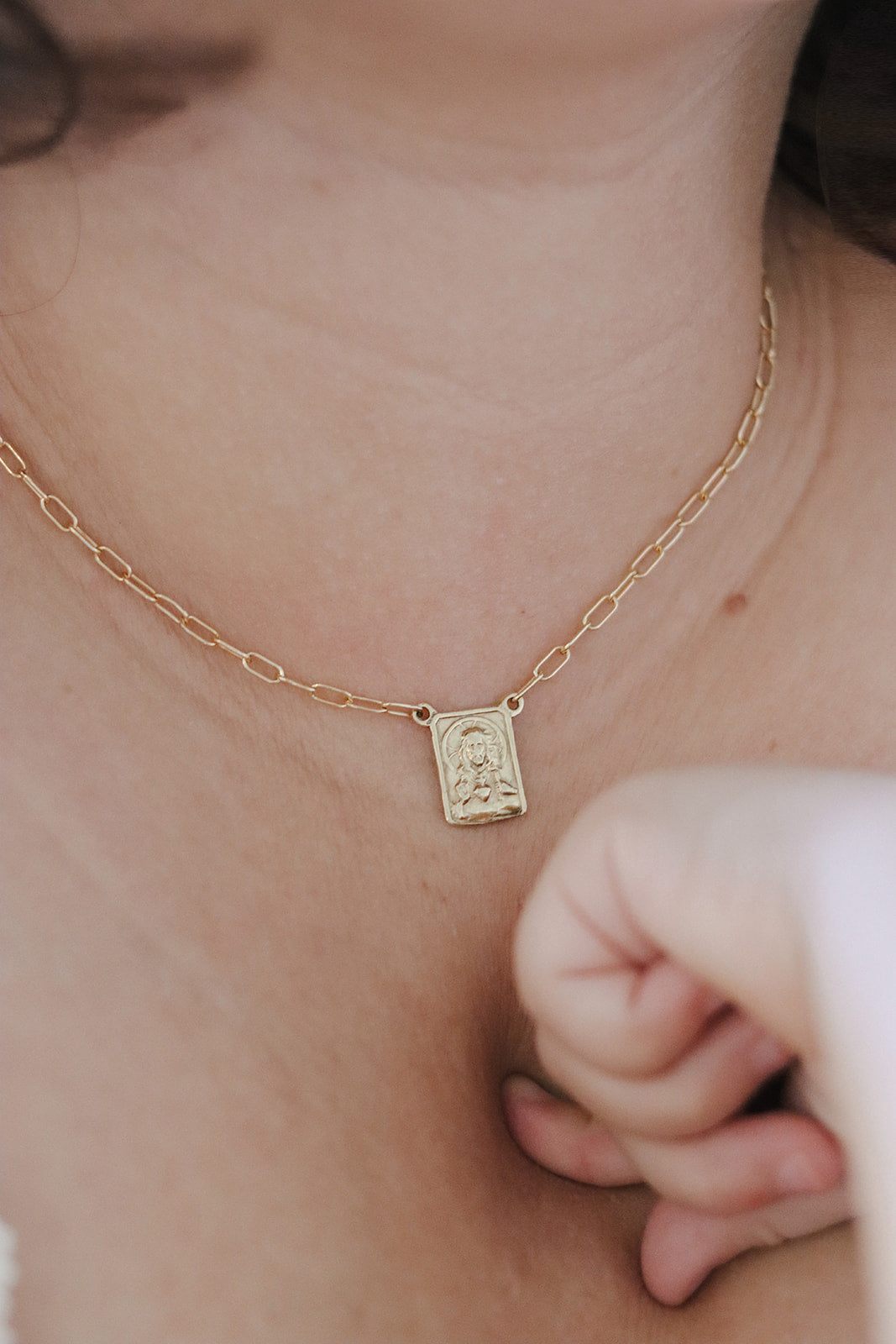 Gold paperclip scapular necklace with square pendant worn on chest
