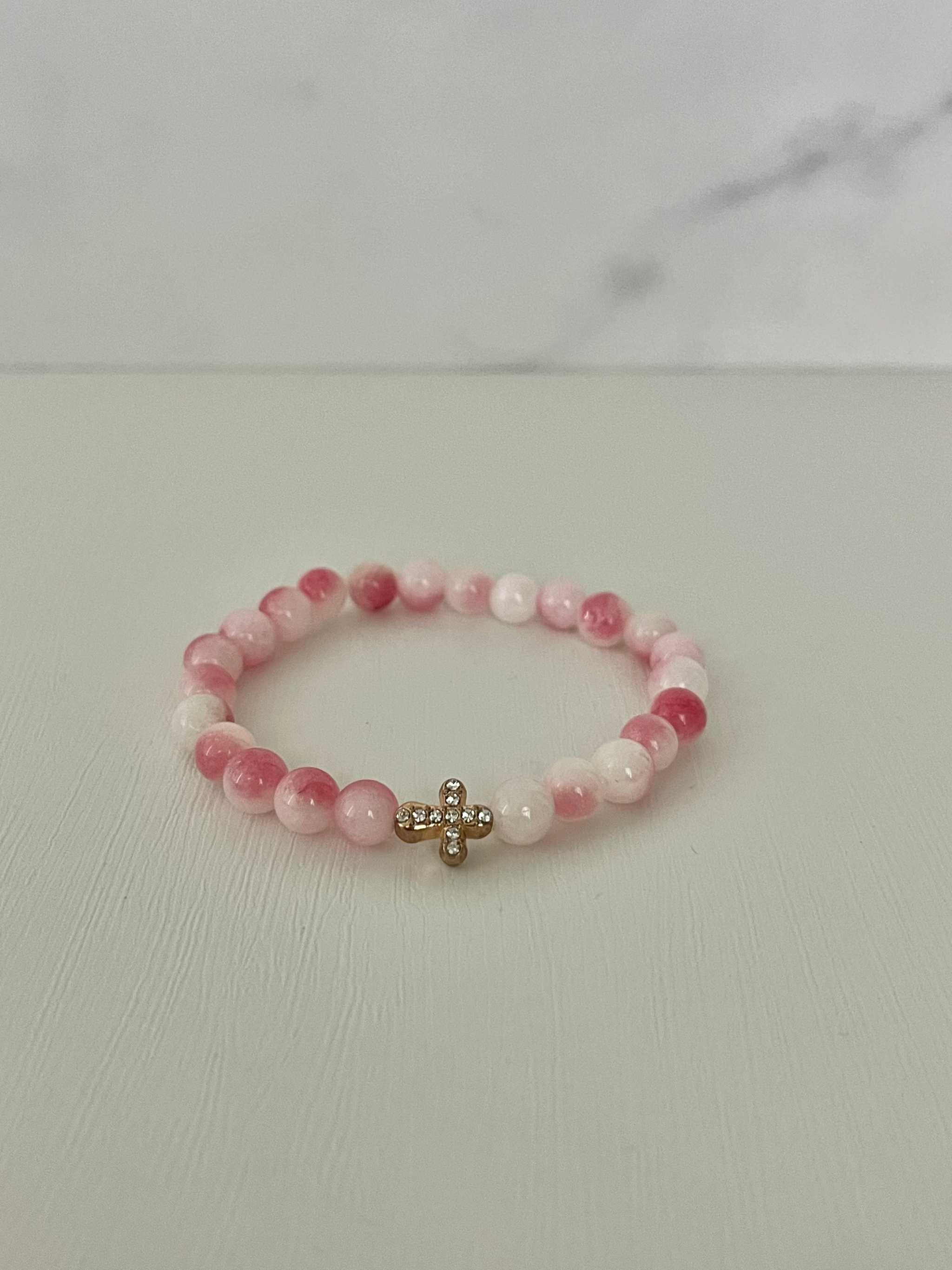 Pink beaded cross bracelet with gold cross charm and stretchy elastic band.