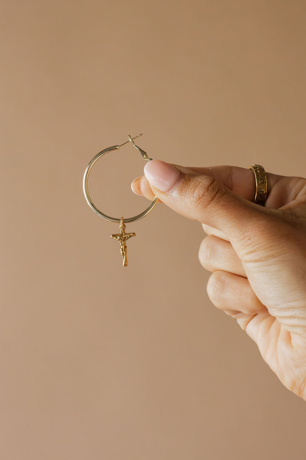 Gold-tone hoop earrings with small dangling crucifix charm