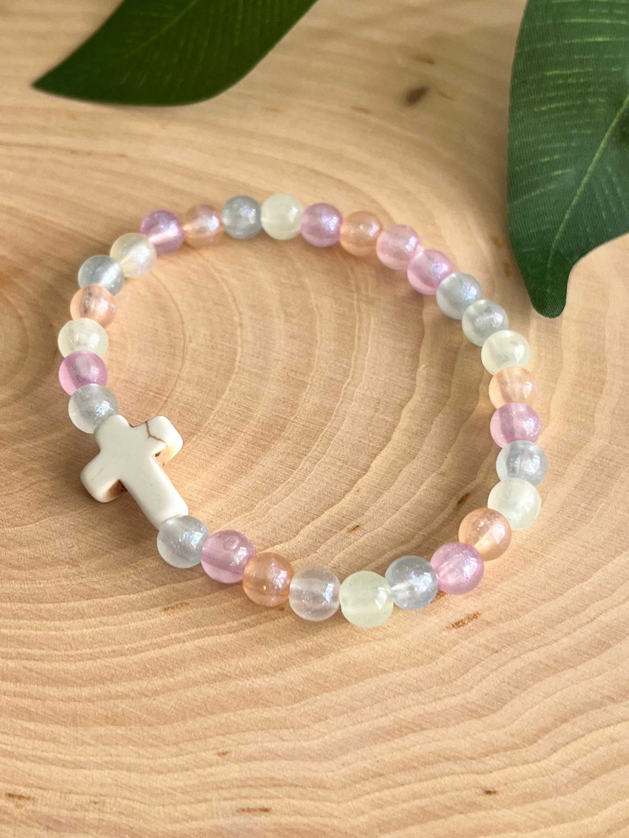 Colorful bead bracelet featuring a white cross charm and multicolor pastel beads.