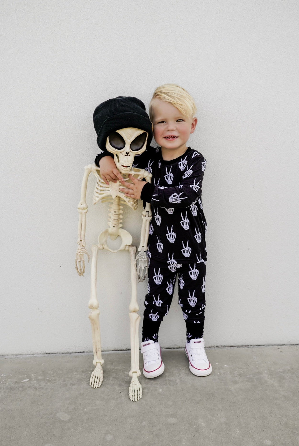Kids black pajama set with white skeleton-hand print, full-length pants.