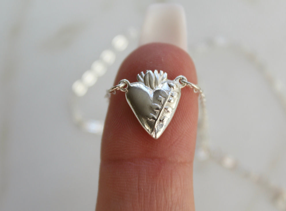 Sterling silver heart pendant necklace with raised design, hanging from a fine chain