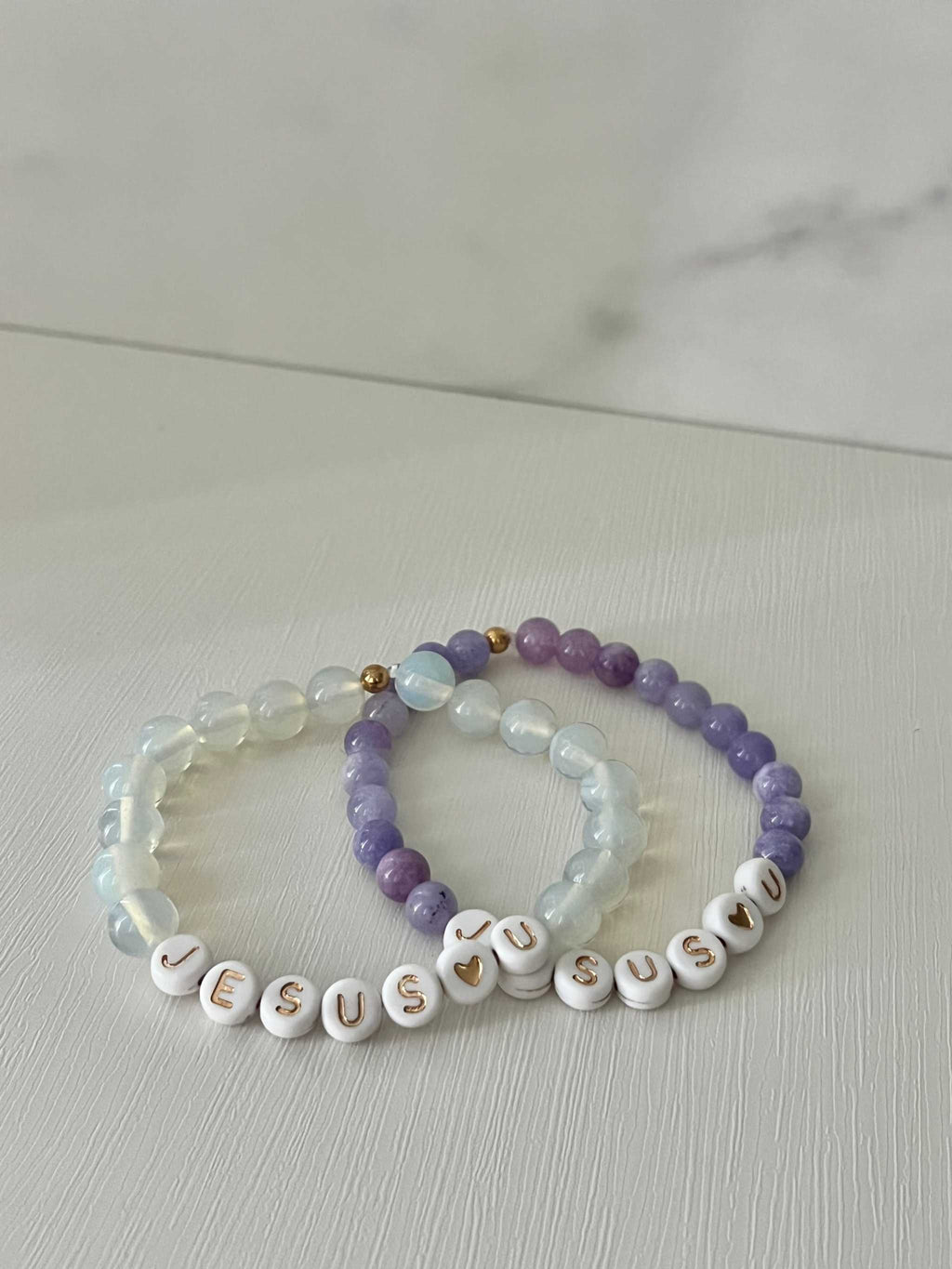 Bead bracelets set: purple and clear beads with white letter beads spelling "Jesus U"