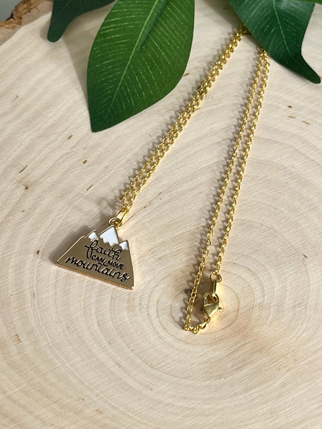 Gold chain necklace with heart pendant engraved with scripture on wood grain