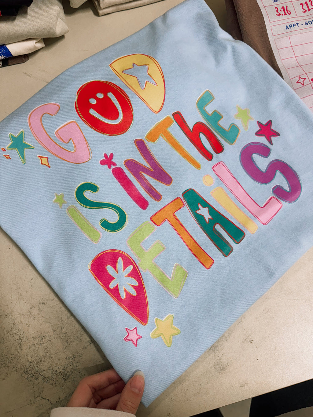 Light blue T-shirt with colorful "God Is In The Details" graphic