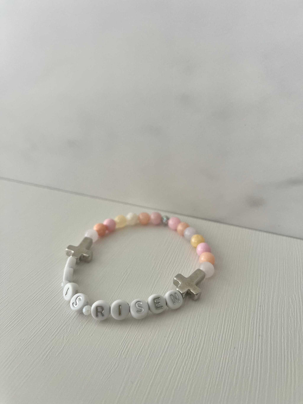 Pastel bead bracelet with 'HE IS RISEN' letter beads and silver cross charm