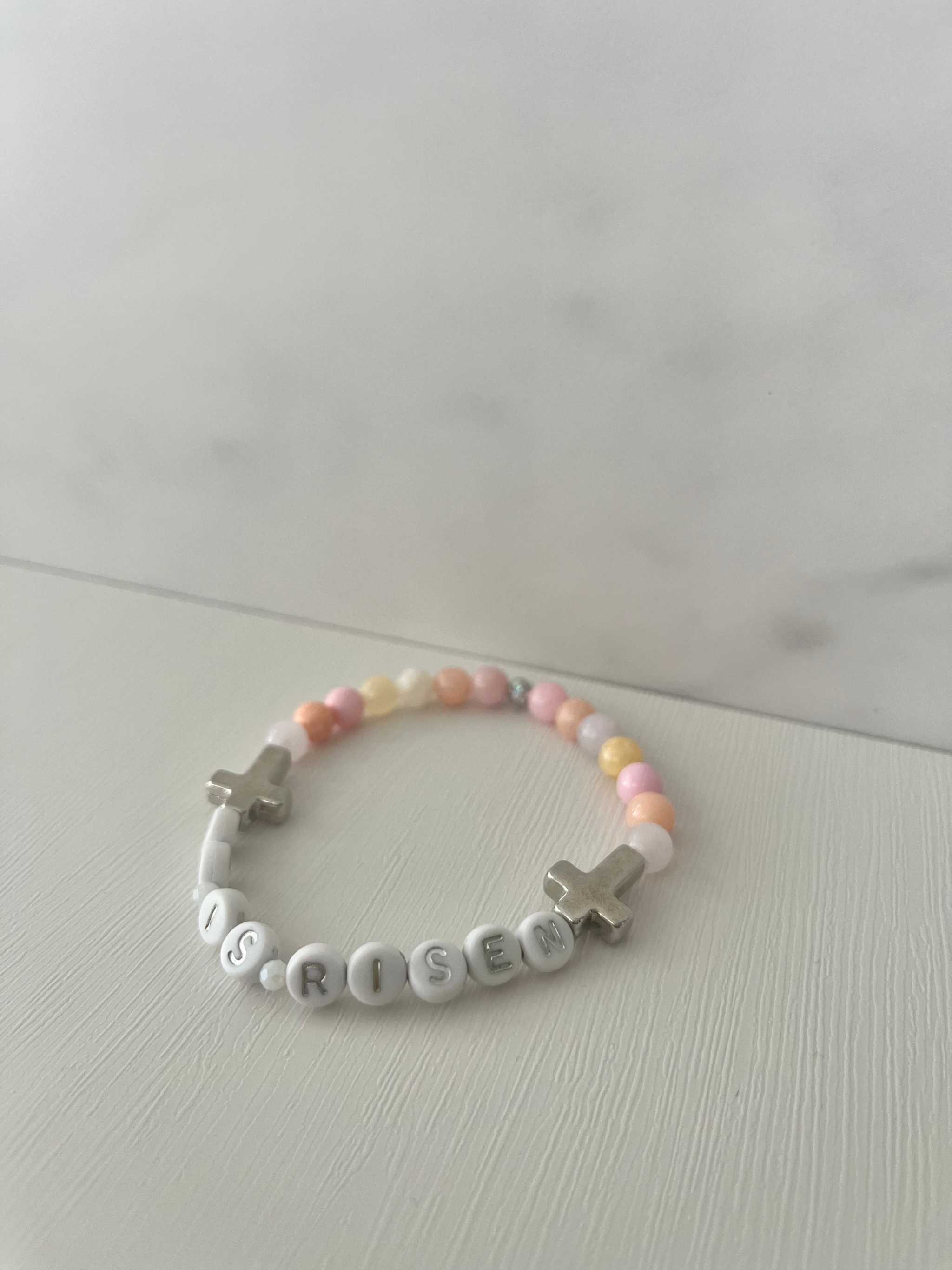Pastel bead bracelet with 'HE IS RISEN' letter beads and silver cross charm