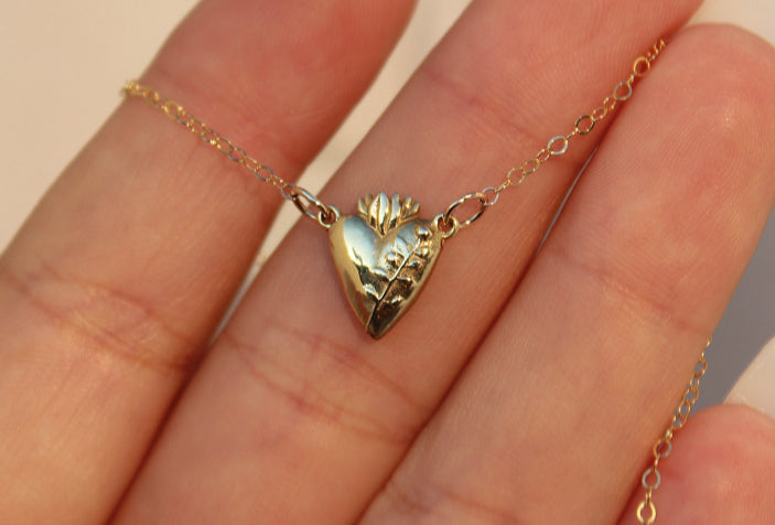 Gold heart pendant necklace with chain and flower-like detail at the top