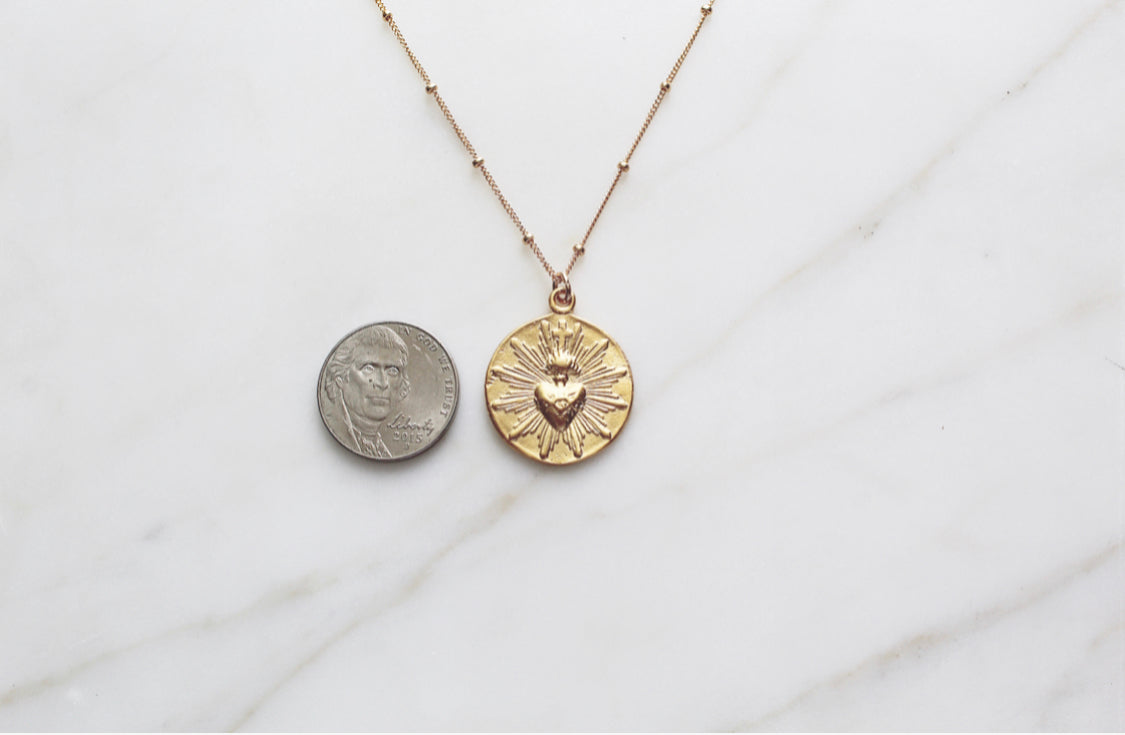 Gold-tone sacred heart coin pendant necklace on fine chain, with a second coin