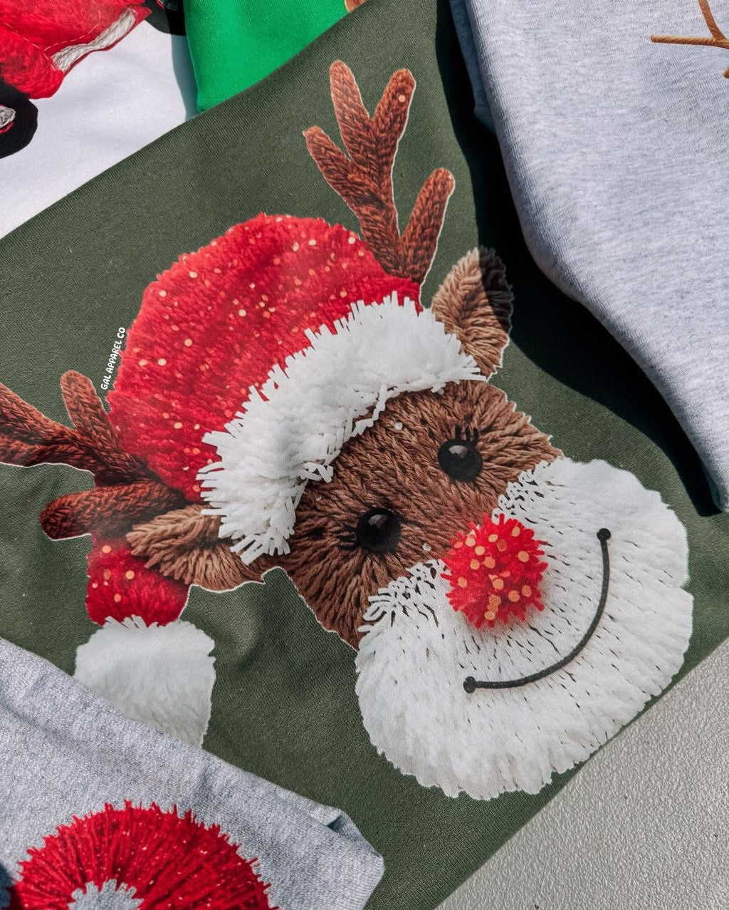 Faux yawn reindeer graphic on dark green tee, close-up of reindeer face with scarf