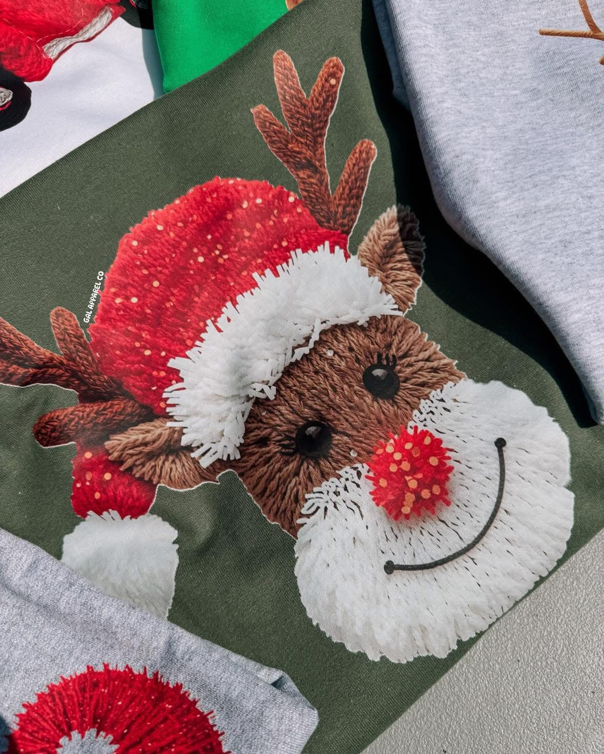 Faux yawn reindeer graphic on dark green tee, close-up of reindeer face with scarf