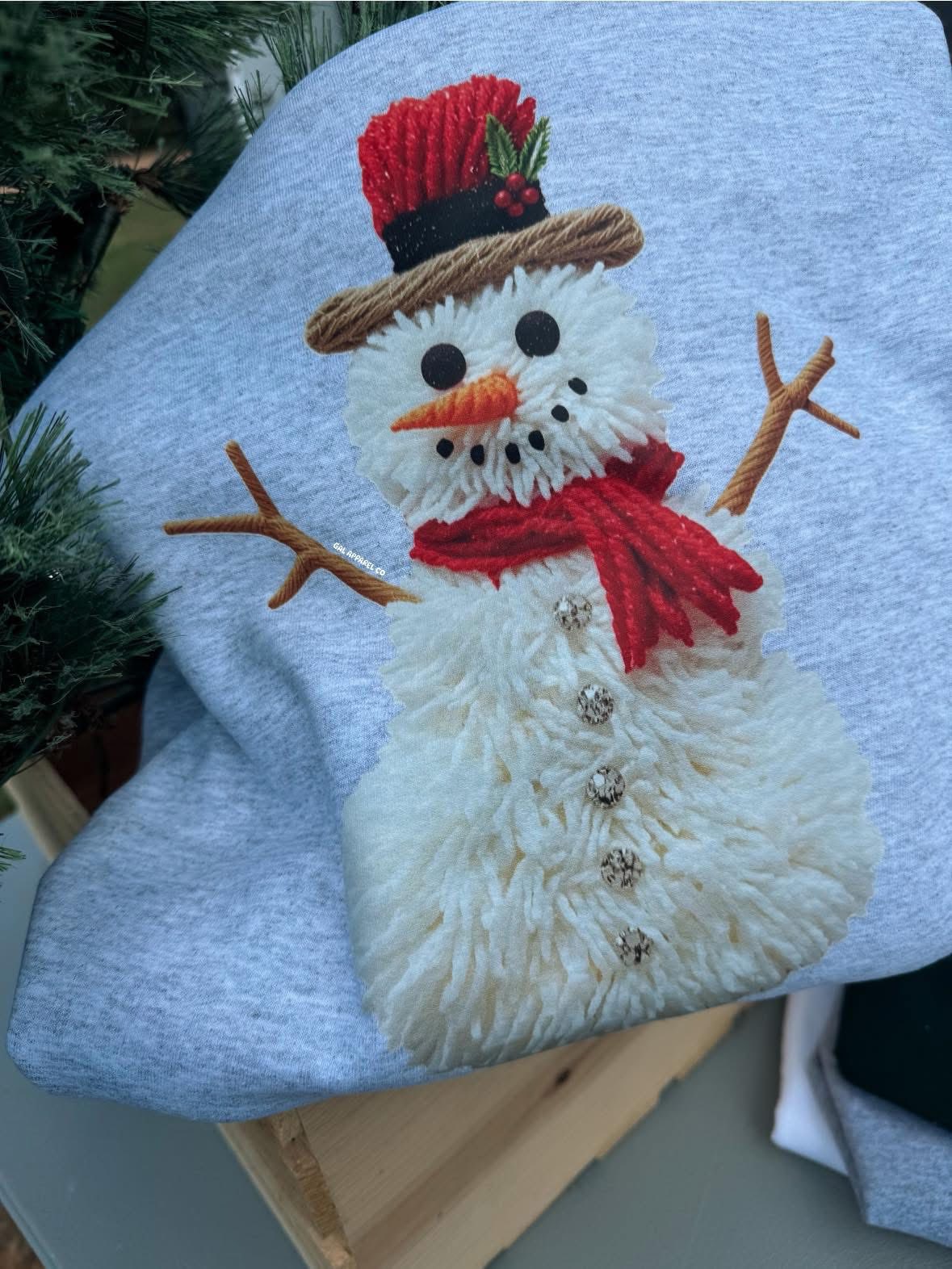 Light blue faux yarn snowman sweatshirt with red hat, red scarf, and twig arms applique