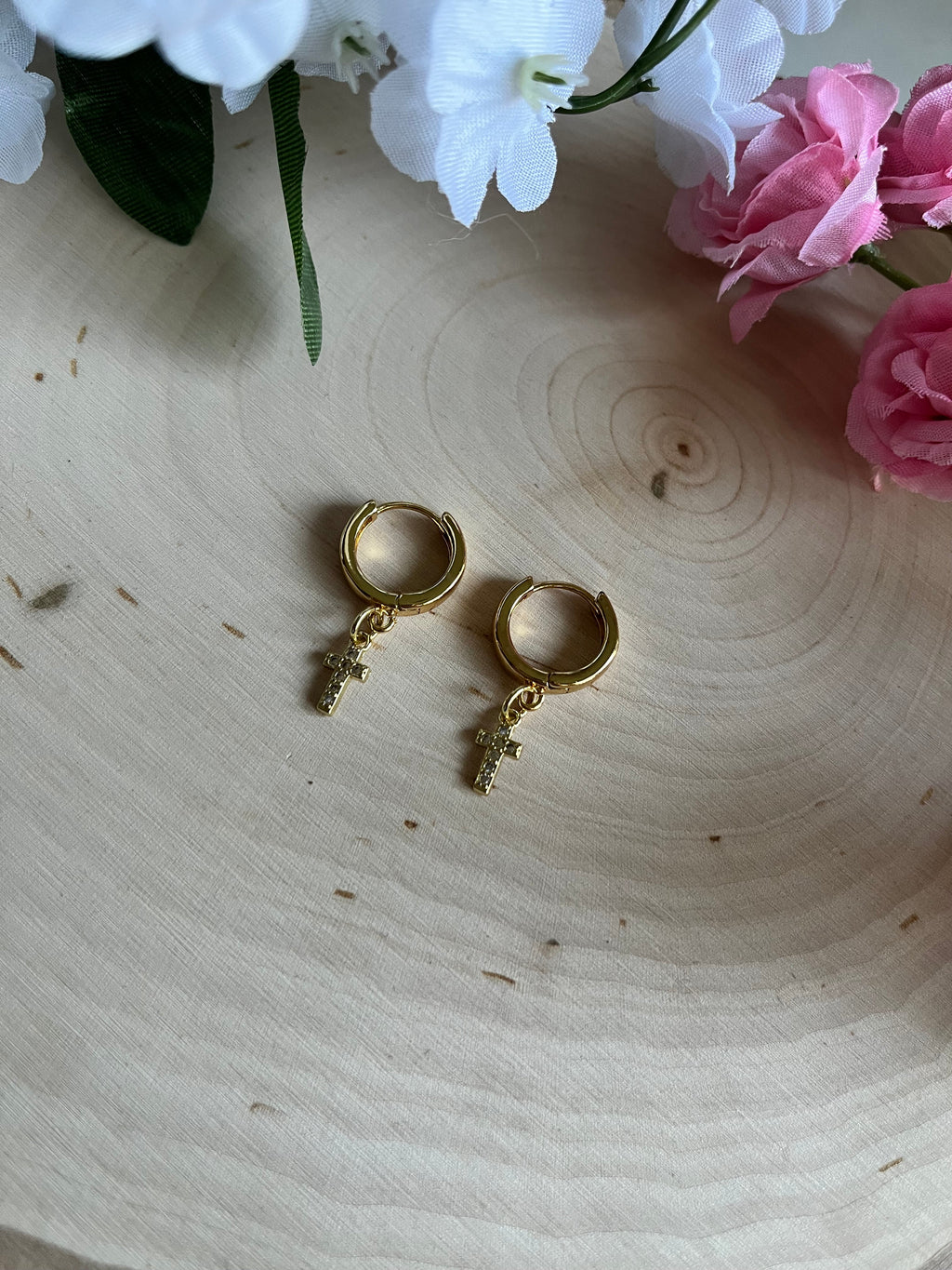 Gold hoop earrings with cross dangle charms, angled close-up