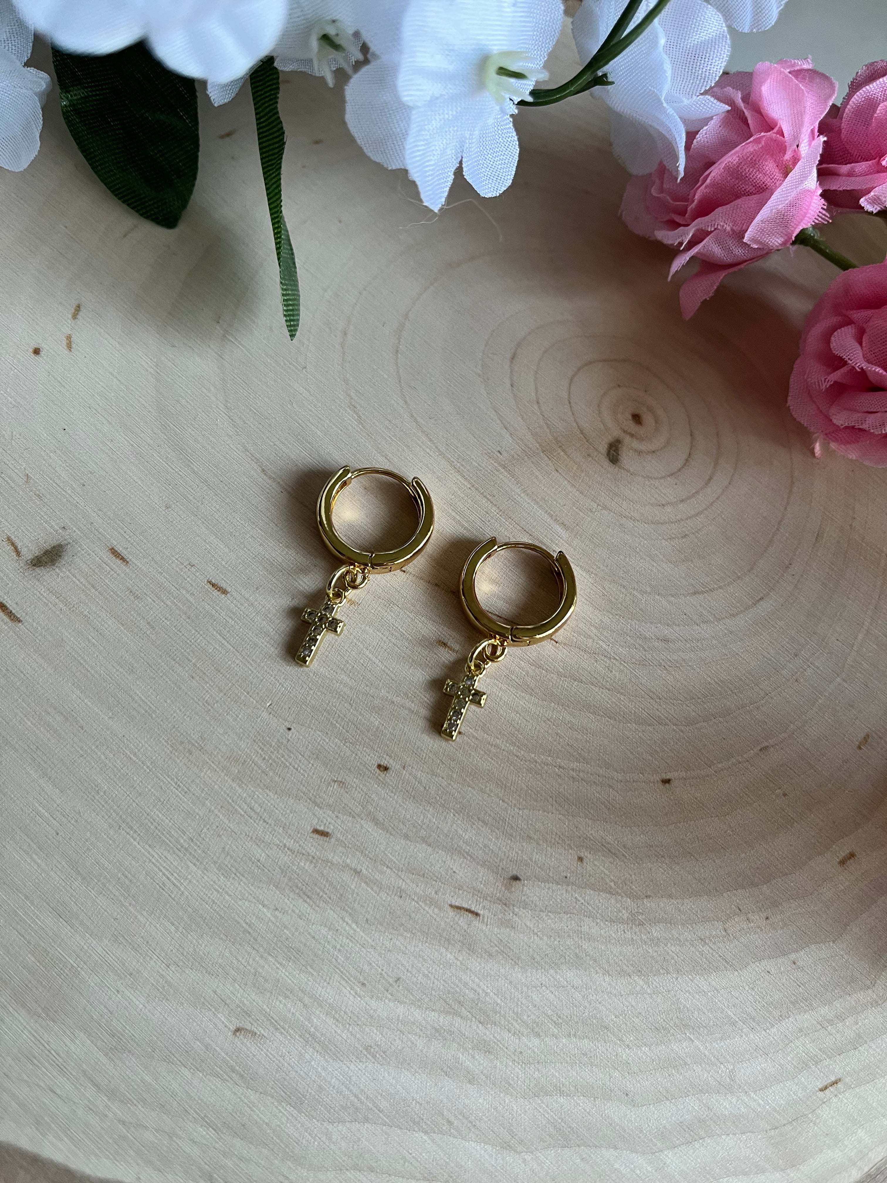 Gold hoop earrings with cross dangle charms, angled close-up