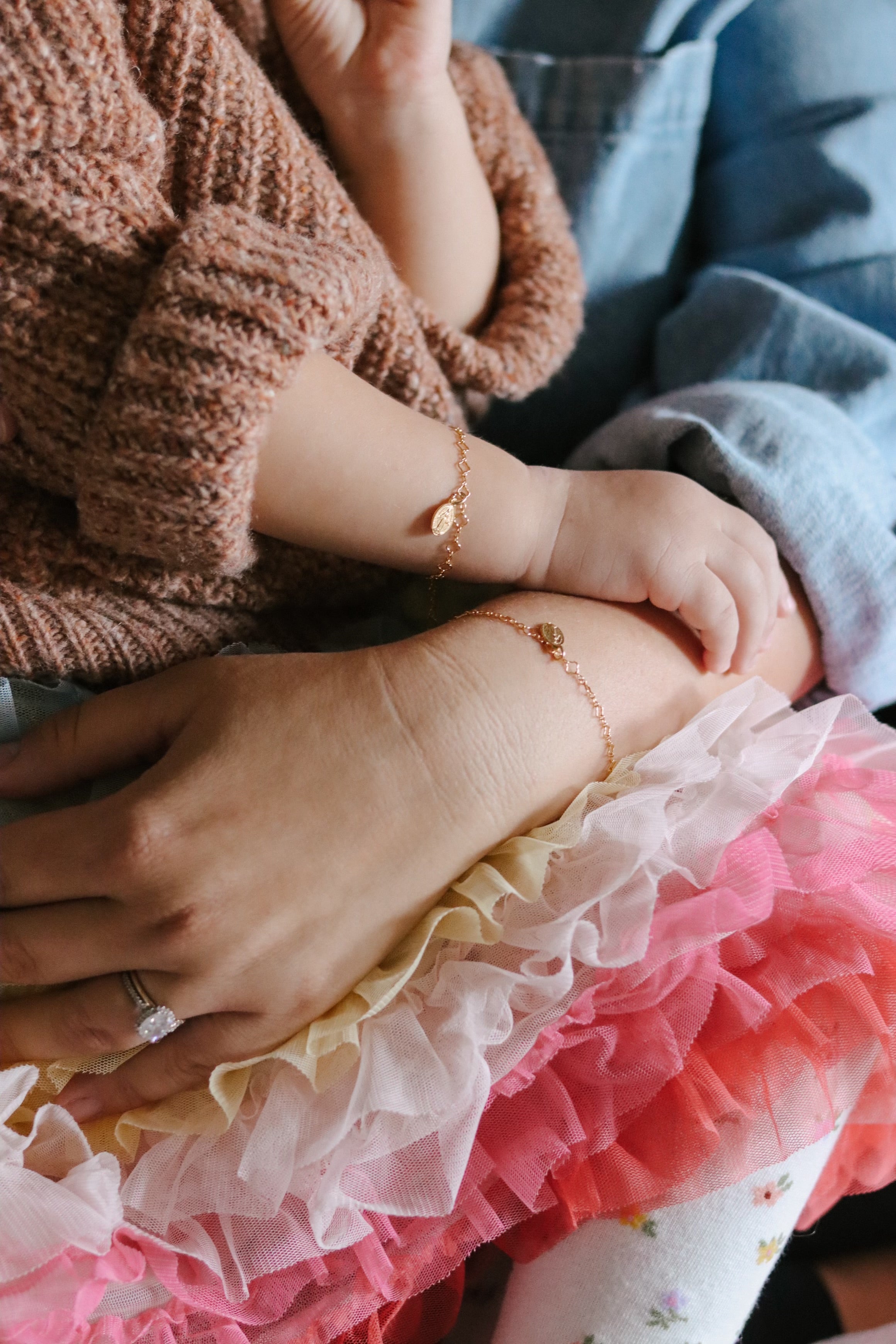 Gold charm bracelet with oval medal pendant around child’s wrist.