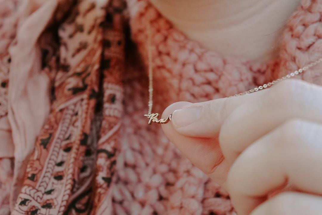 Gold Pax pendant necklace close-up on pink textured knit sweater