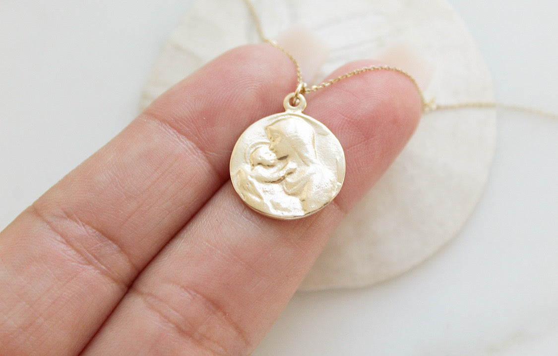 14k gold medallion pendant necklace with Jesus and Mary relief, held in hand