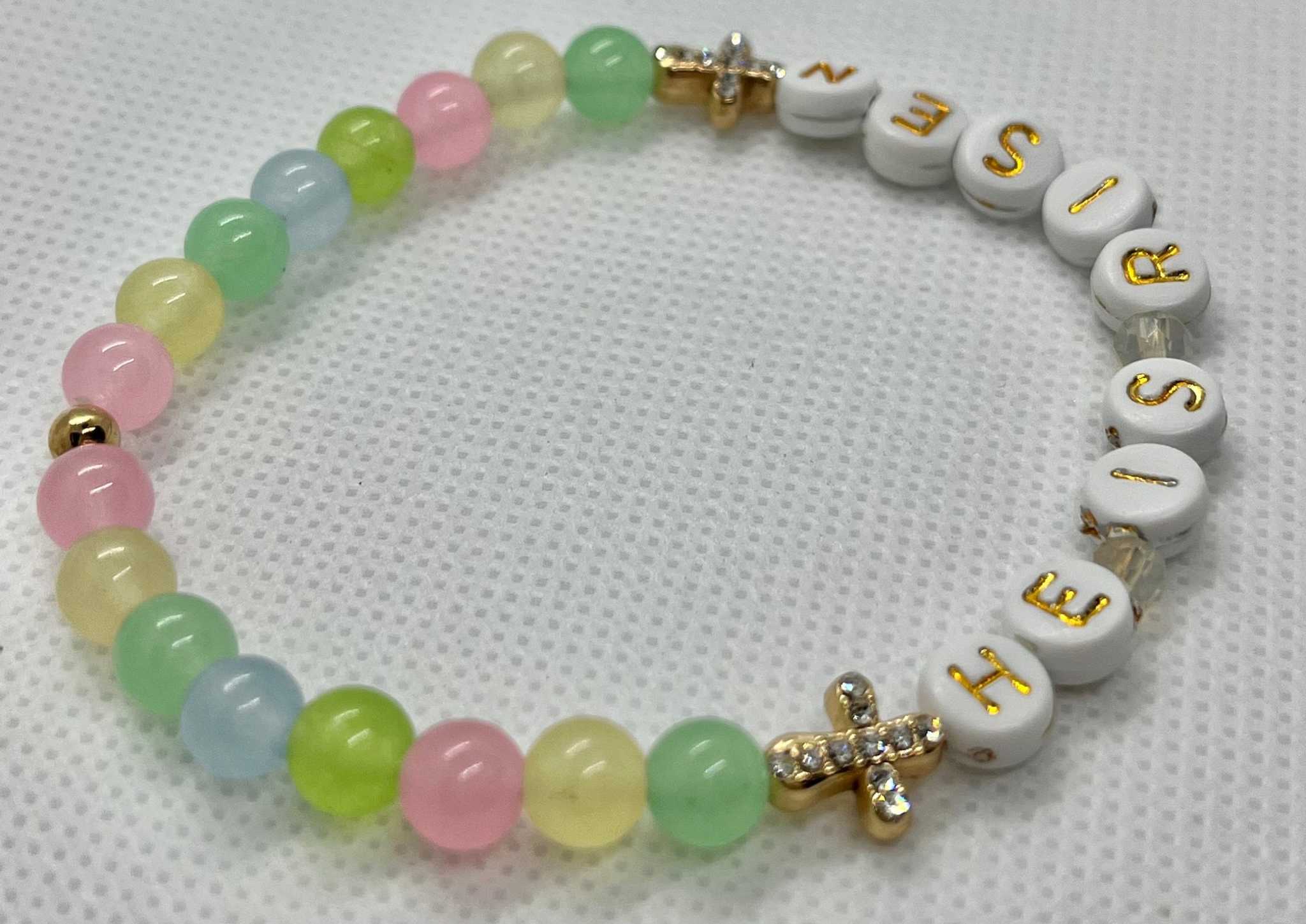 Multicolor bead bracelet reading “HE IS RISEN” with two gold cross charms
