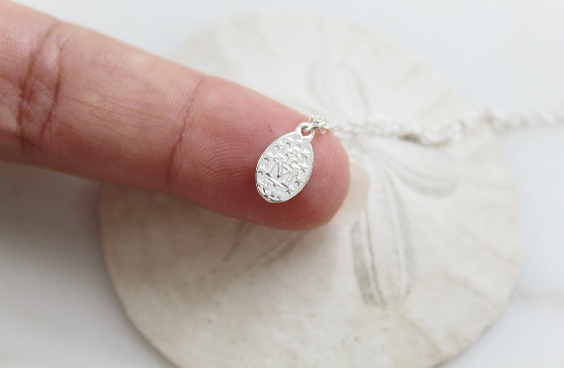 Oval miraculous medal pendant in silver-tone with textured center, close-up