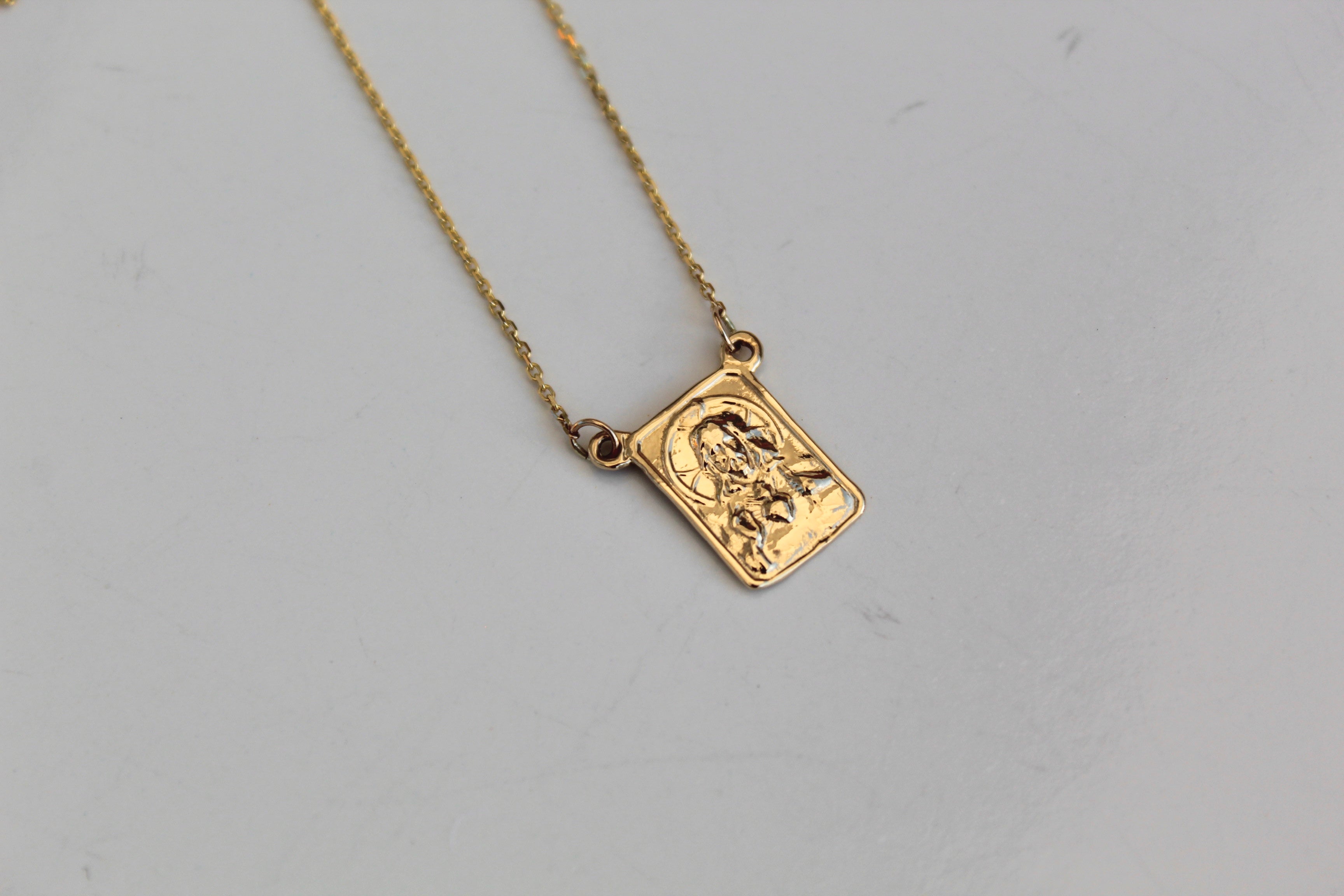 Square 14K gold scapular pendant with embossed figure on a delicate chain