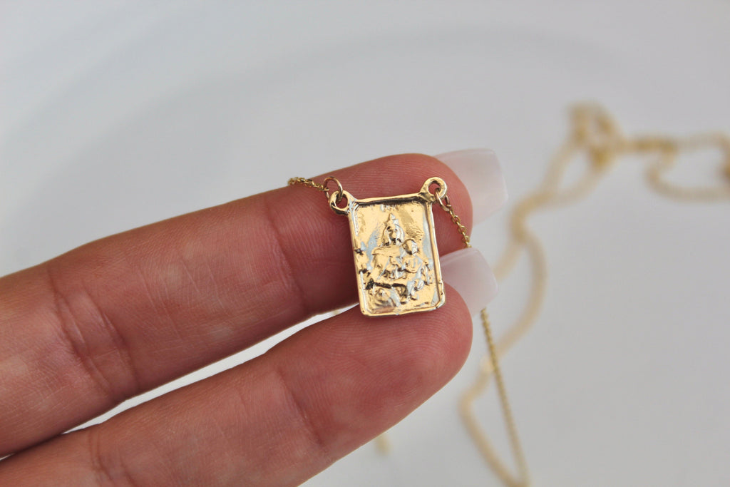 14K gold scapular pendant held in hand, square charm with saint image