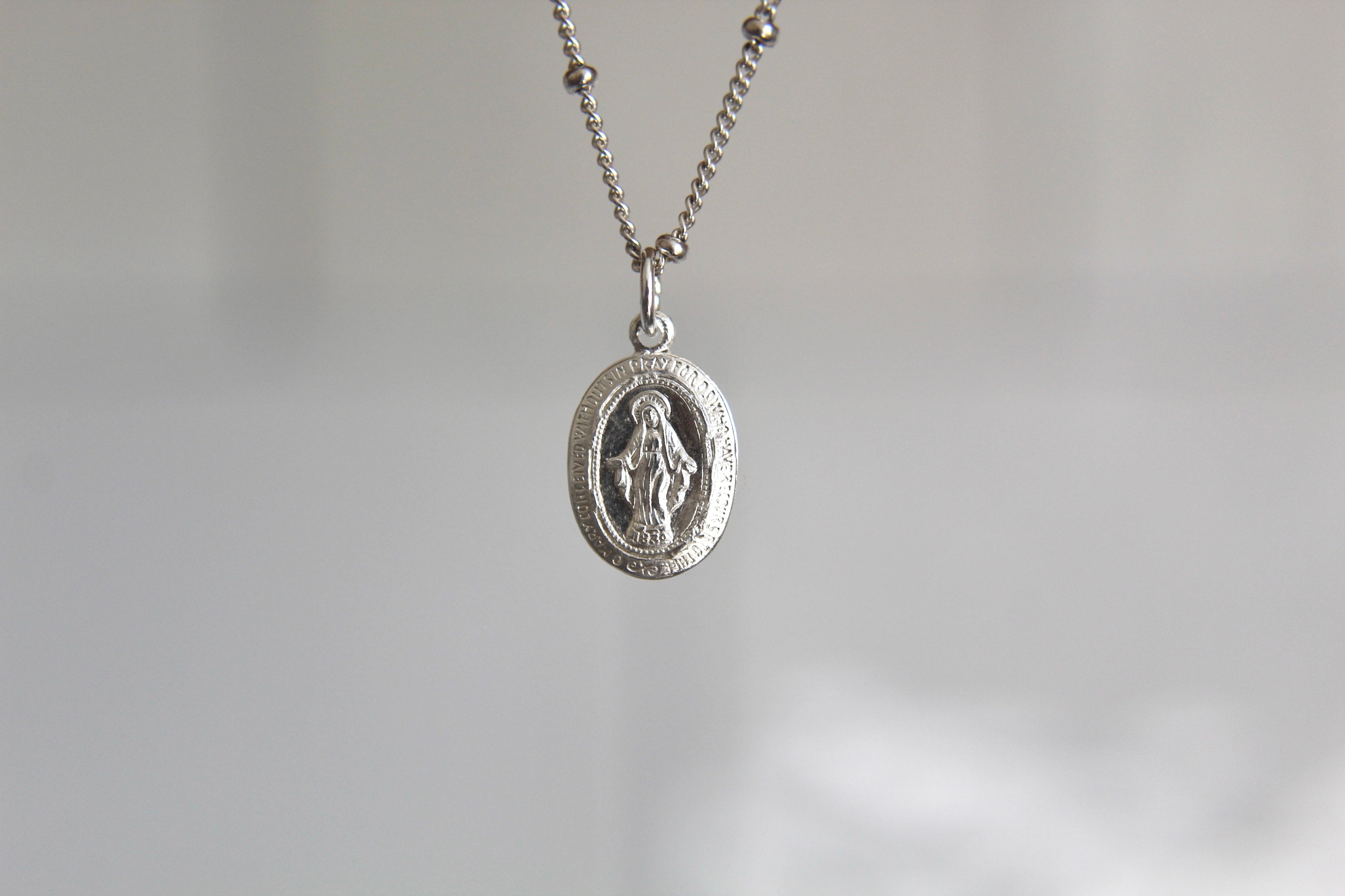 Silver miraculous medal necklace with oval pendant and fine chain links