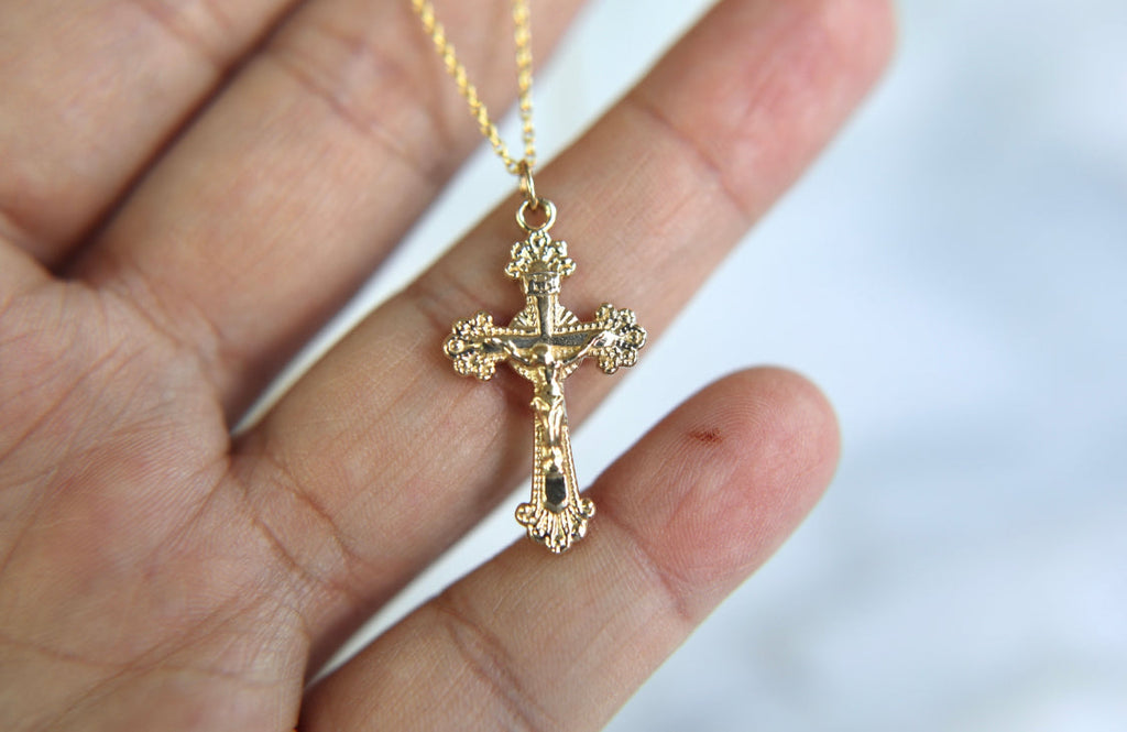 14k gold crucifix pendant on a chain, textured cross with top ornament.