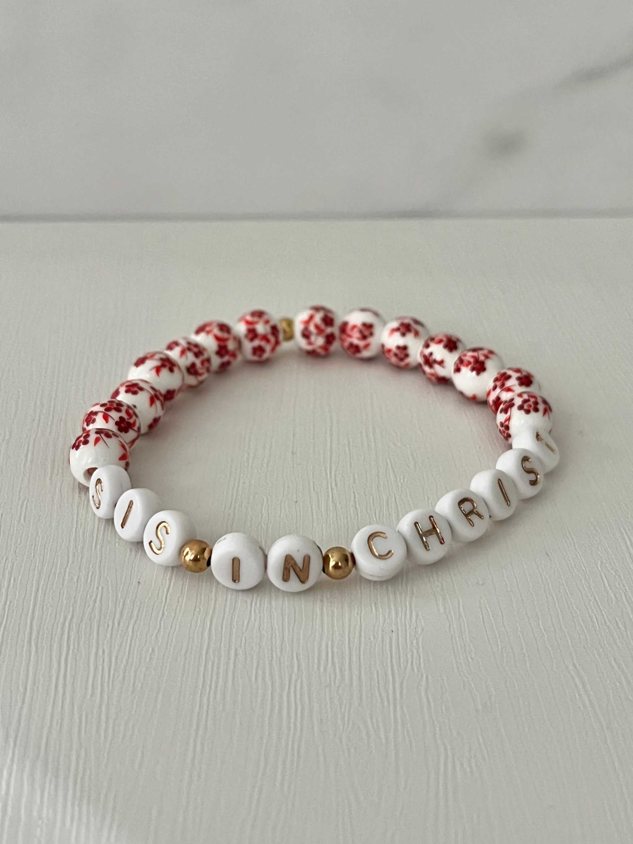 Red bead bracelet with white letter beads spelling IN CHRIST and red floral accents