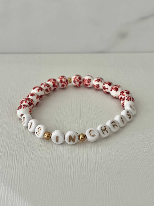 Red bead bracelet with white letter beads spelling IN CHRIST and red floral accents