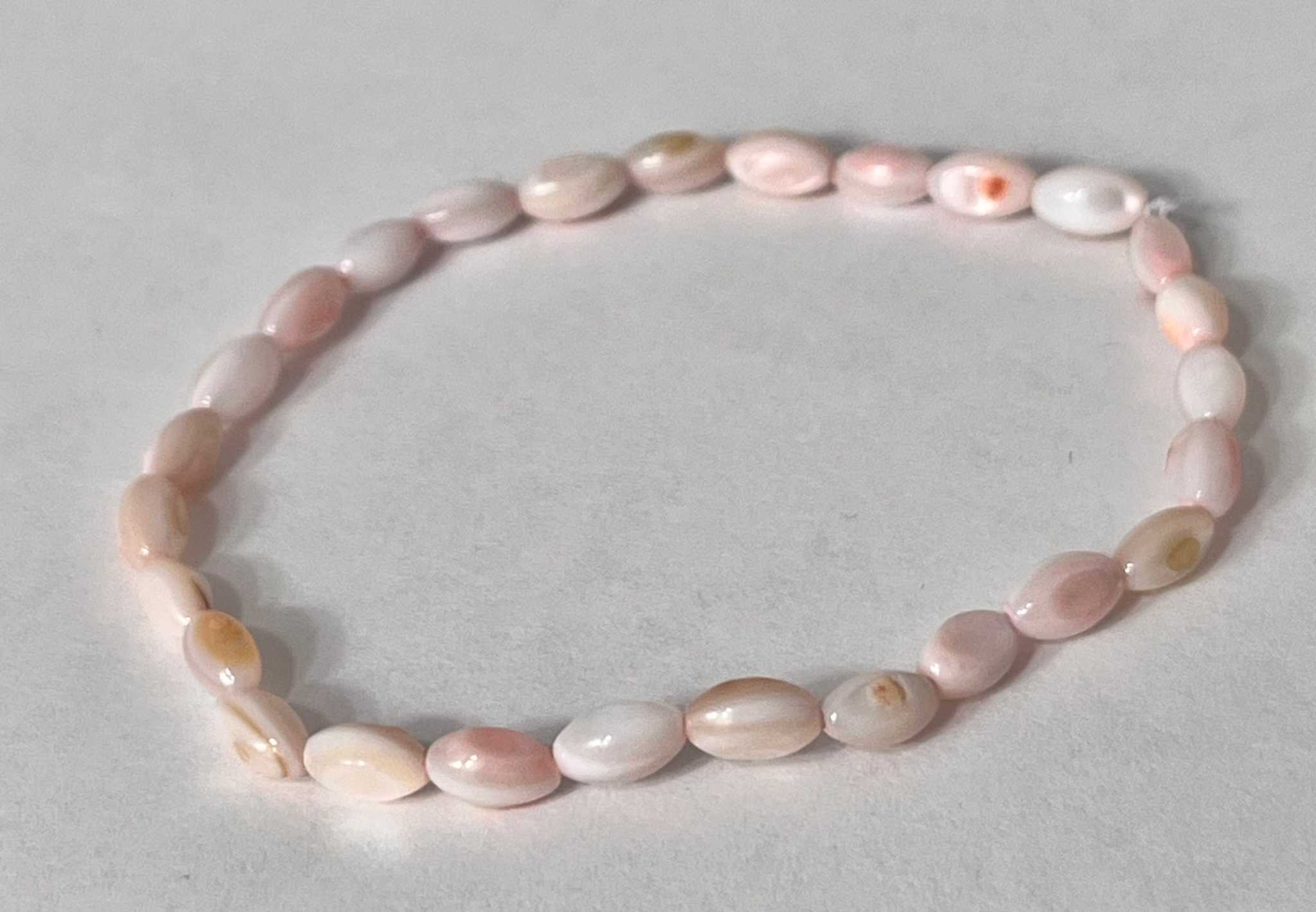 Bead bracelet with pink and cream pearl-like oval beads in a snug oval shape