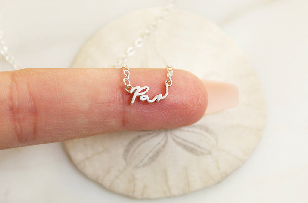 925 sterling silver Pax necklace with cursive Pax charm on chain held in hand