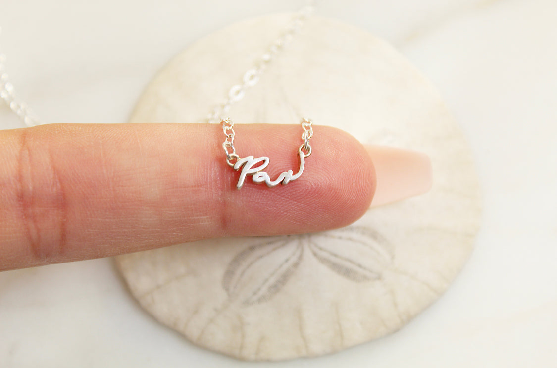 925 sterling silver Pax necklace with cursive Pax charm on chain held in hand