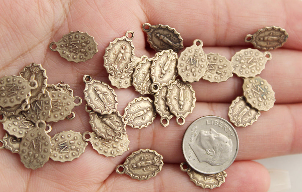Assorted bronze medal charms with loops, multiple designs shown in hand.