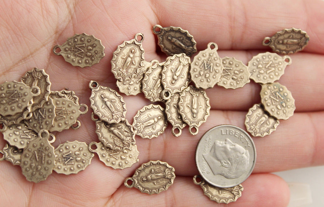 Assorted bronze medal charms with loops, multiple designs shown in hand.
