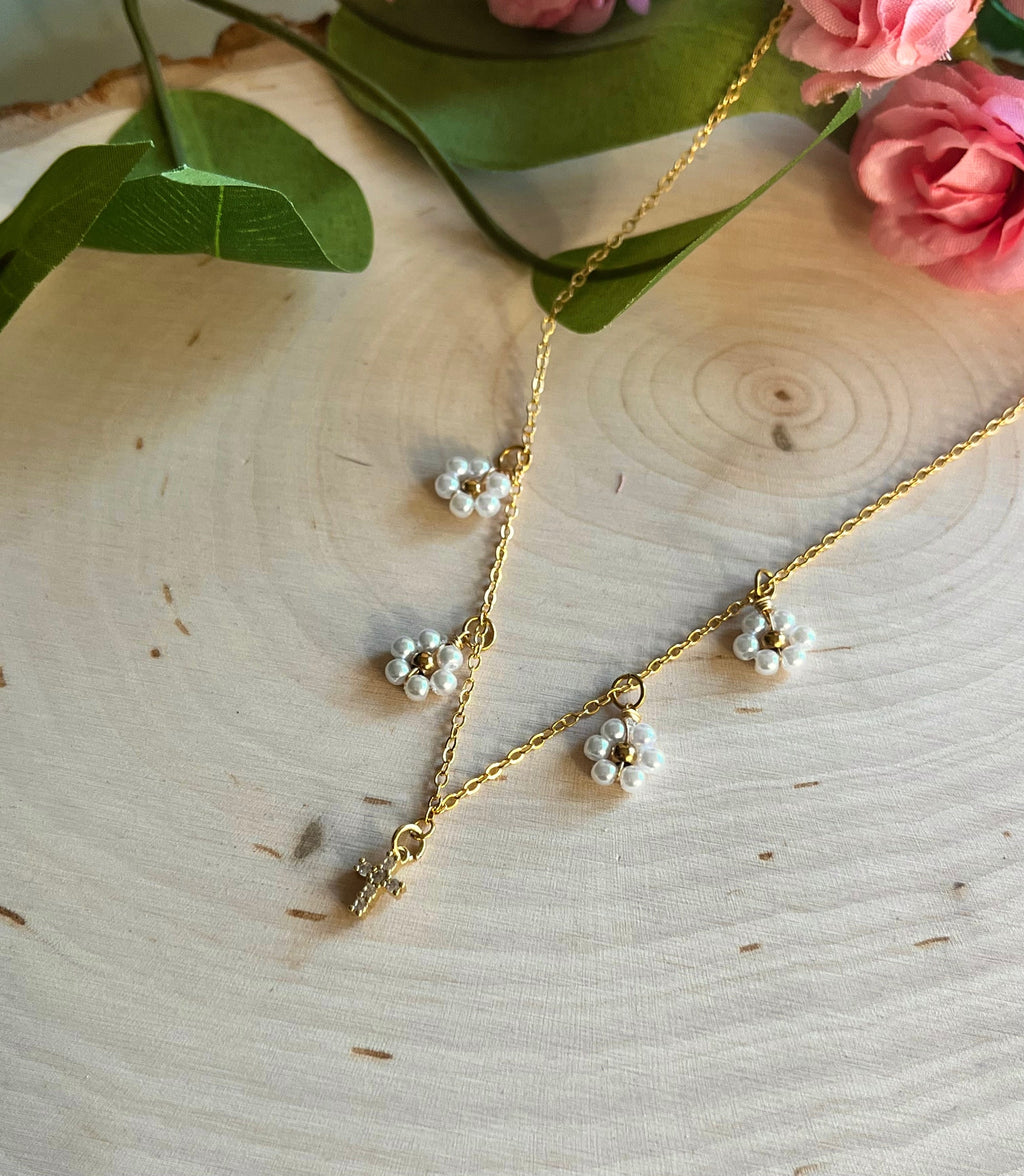 Gold cross pendant necklace with white daisy charms and dangling bead clusters