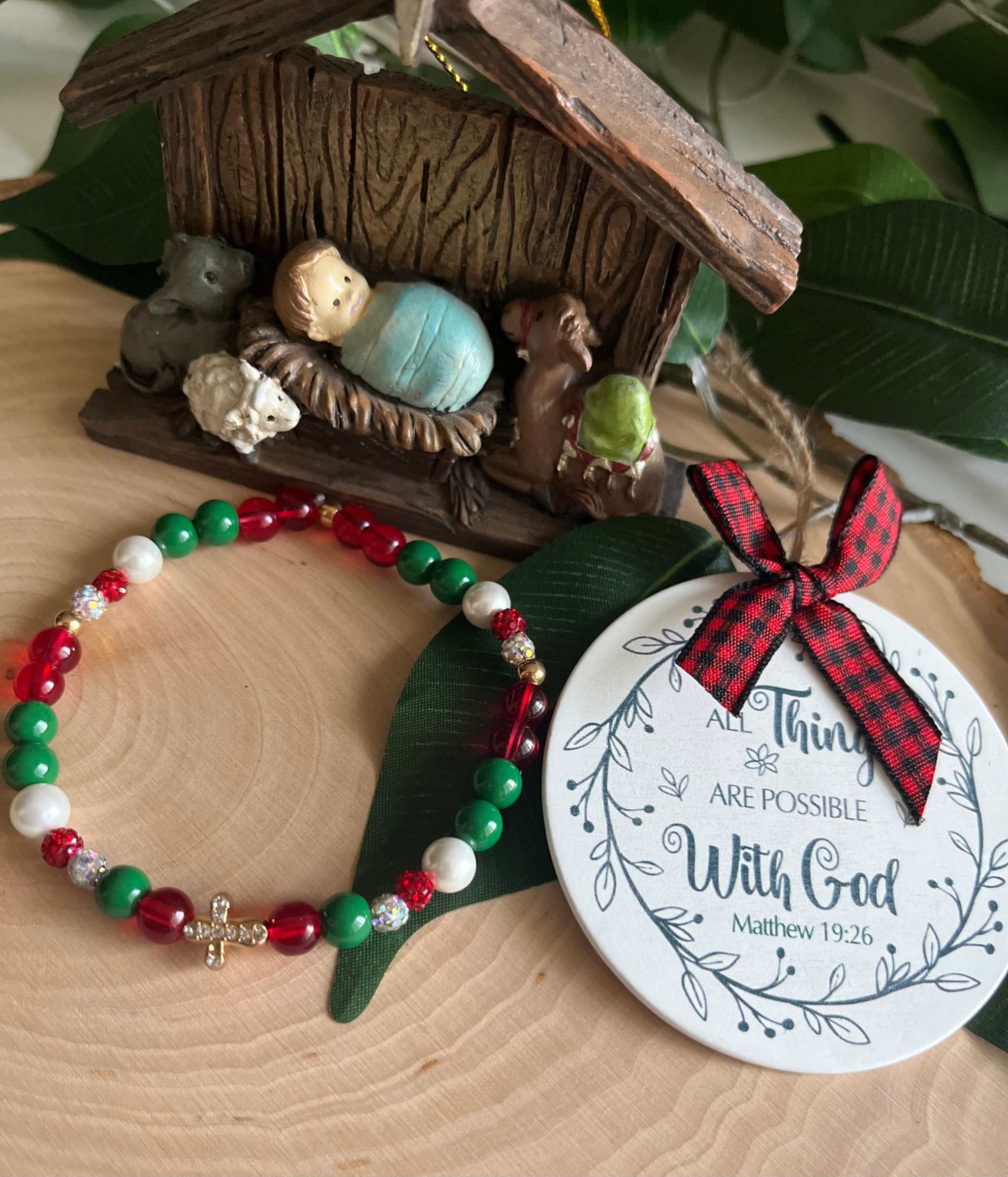 Beaded bracelet with red, green, and white beads and a small silver cross charm