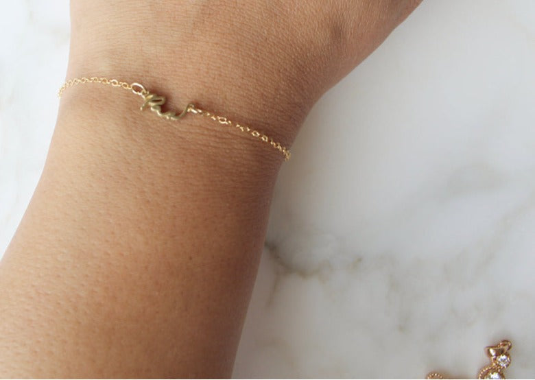 Pax bracelet on wrist, thin gold-tone chain with small charm links