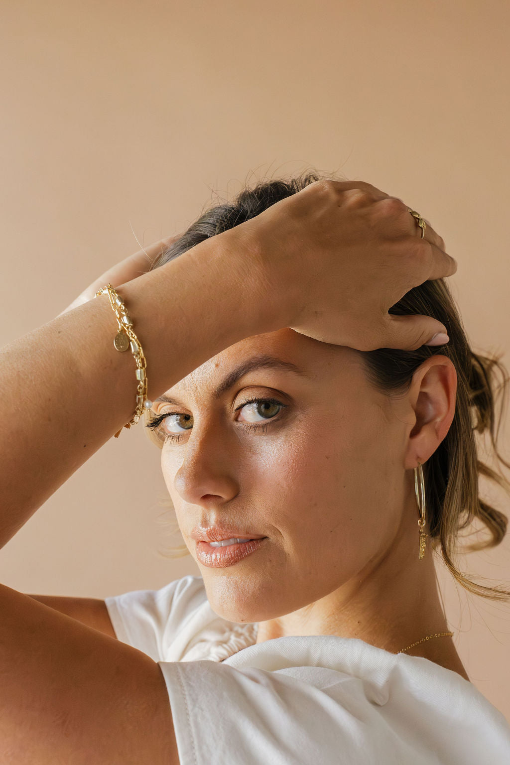 Gold-tone hoop earrings with crucifix cross charm on ear