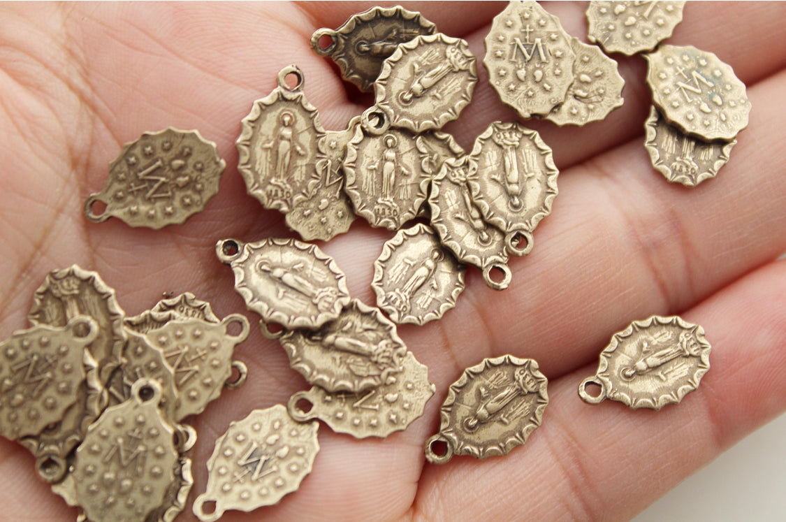 Assorted bronze medal charms with loops, various textured fronts visible.