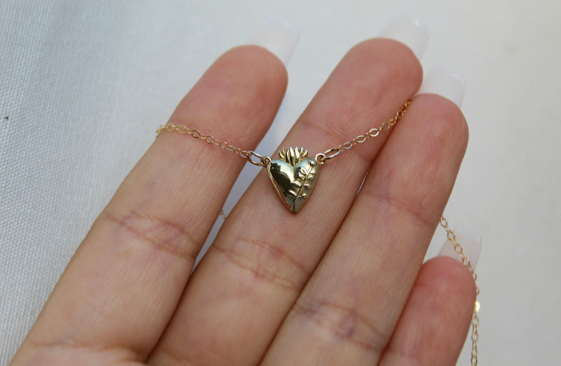 Gold-tone heart pendant necklace close-up on hand