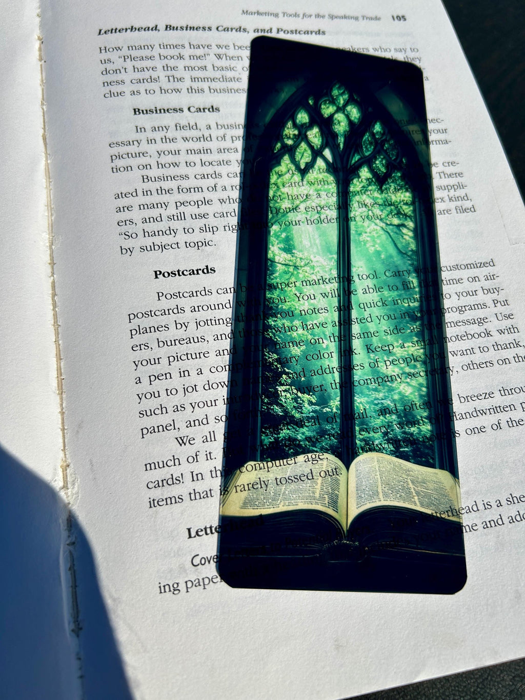 Stained glass arched bookmark with green canopy design resting on open book page