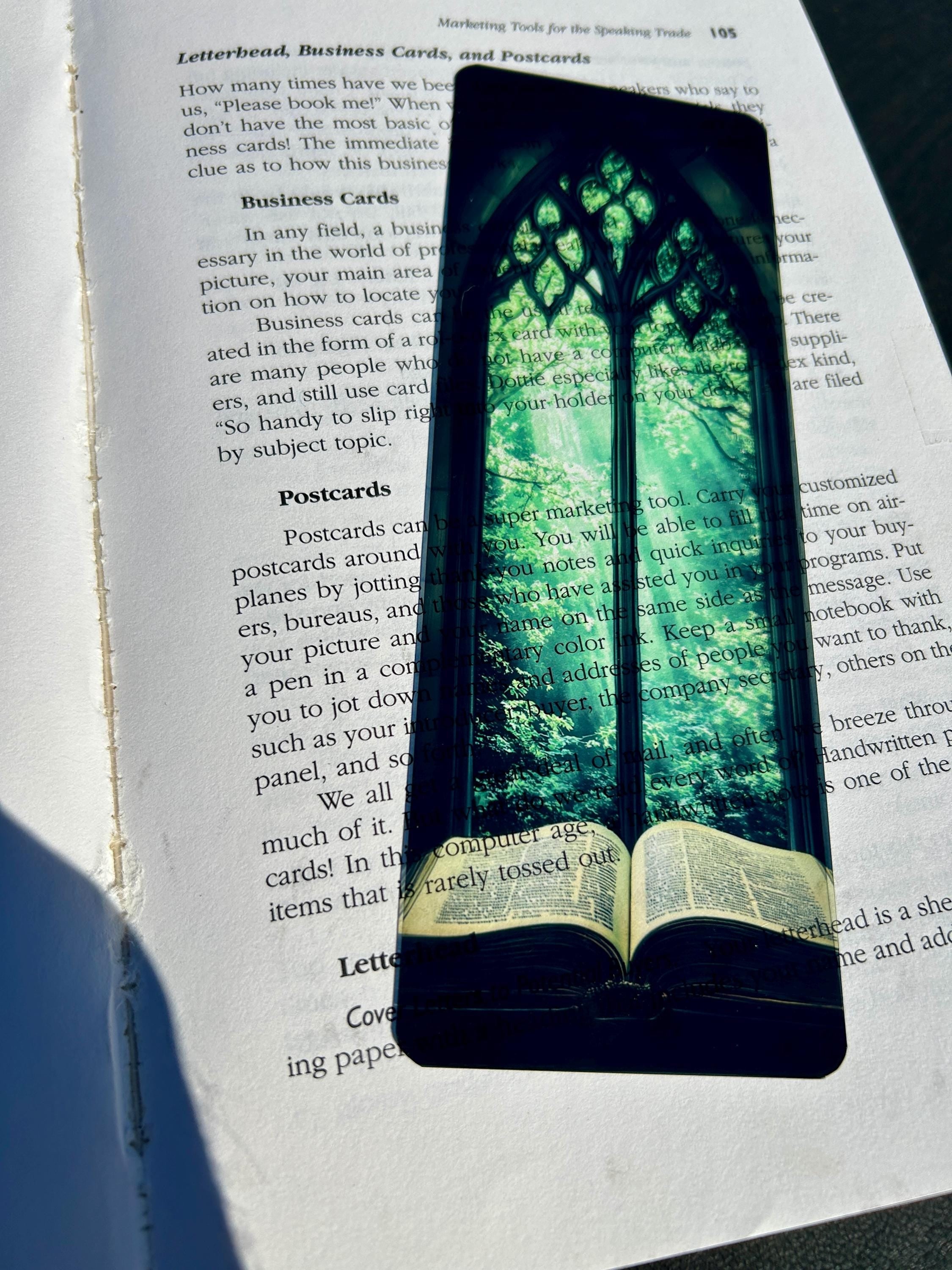 Stained glass arched bookmark with green canopy design resting on open book page