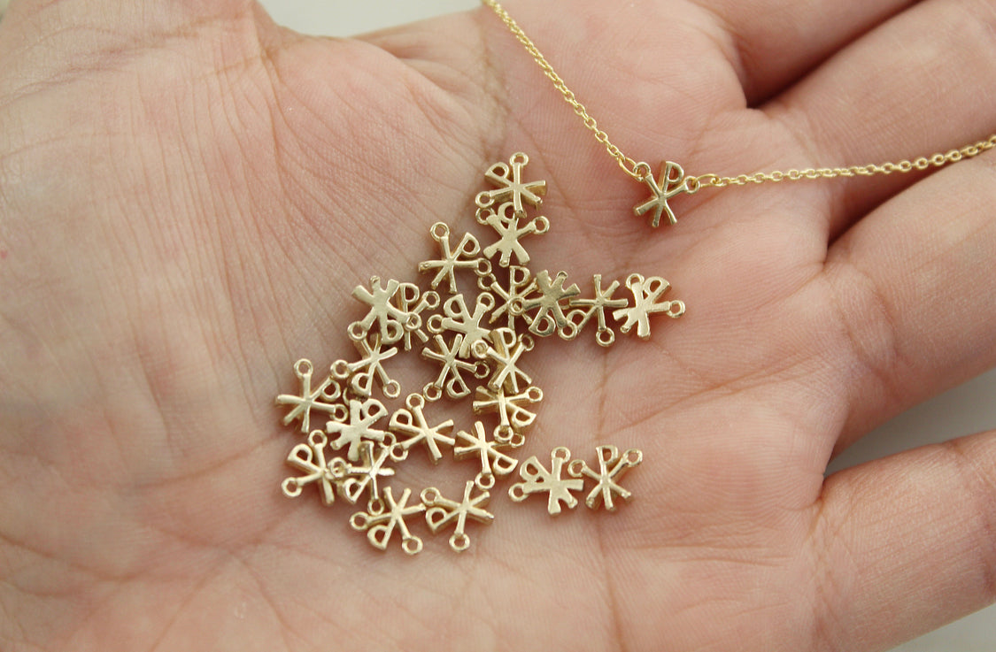 Gold Chi Rho charm pendants clustered in an open palm